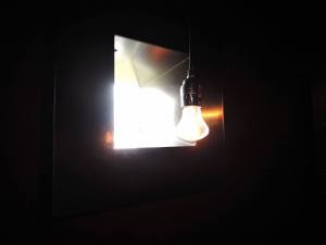By each person's plaque is a tiny window to the outdoors and a bare hanging light bulb. — at Steilneset Memorial in Vardø, Norway.