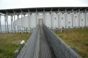 Zumthor took for his inspiration the wooden racks that are used to dry codfish into lutefisk to make the part of the memorial known as the memorial hall. Beneath the rack-shaped structure is a canvas enclosure. Each of the small black squares you seen on the canvas is a tiny window. — at Steilneset Memorial in Vardø, Norway.